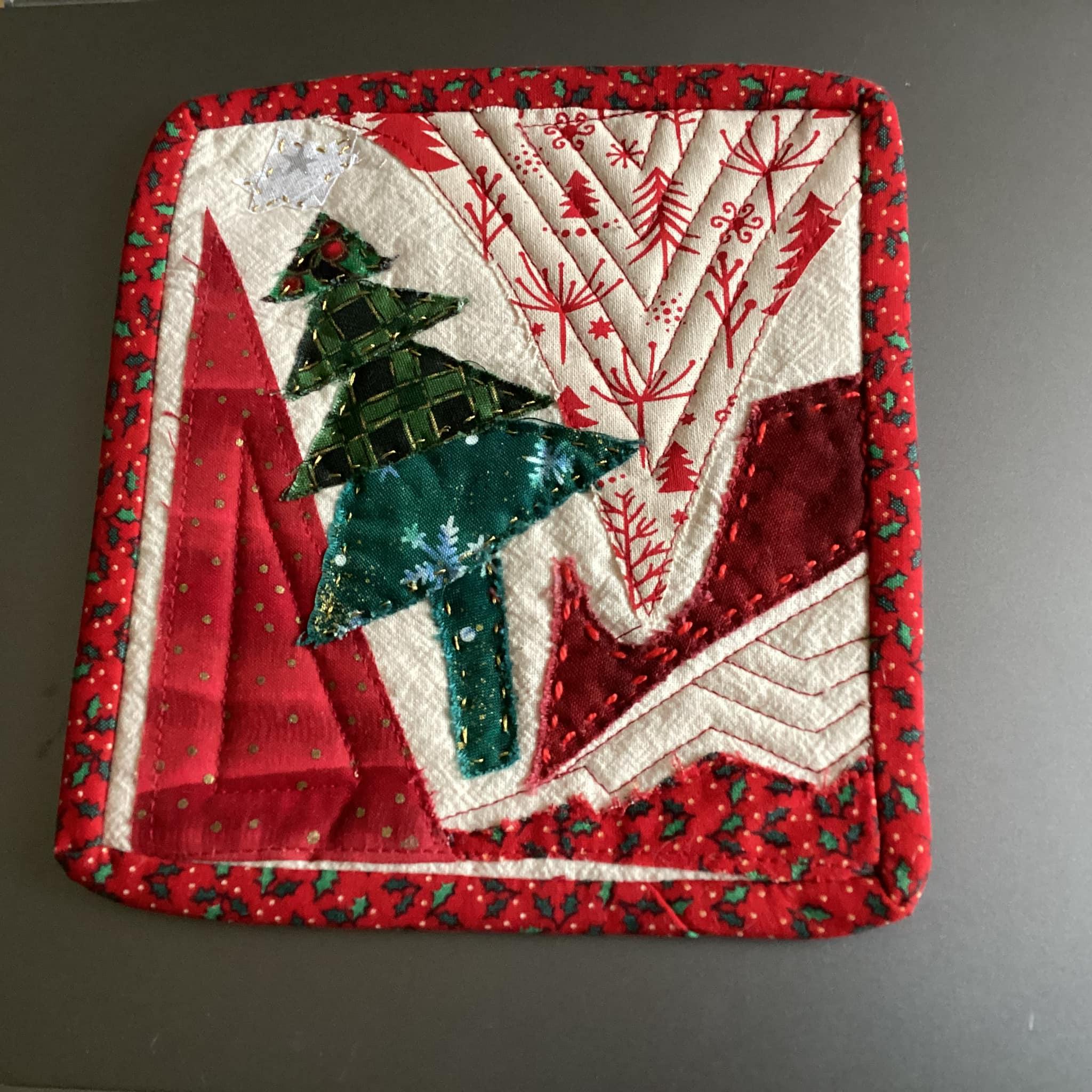 A festive red mug rug with a central motif of a green Christmas tree.