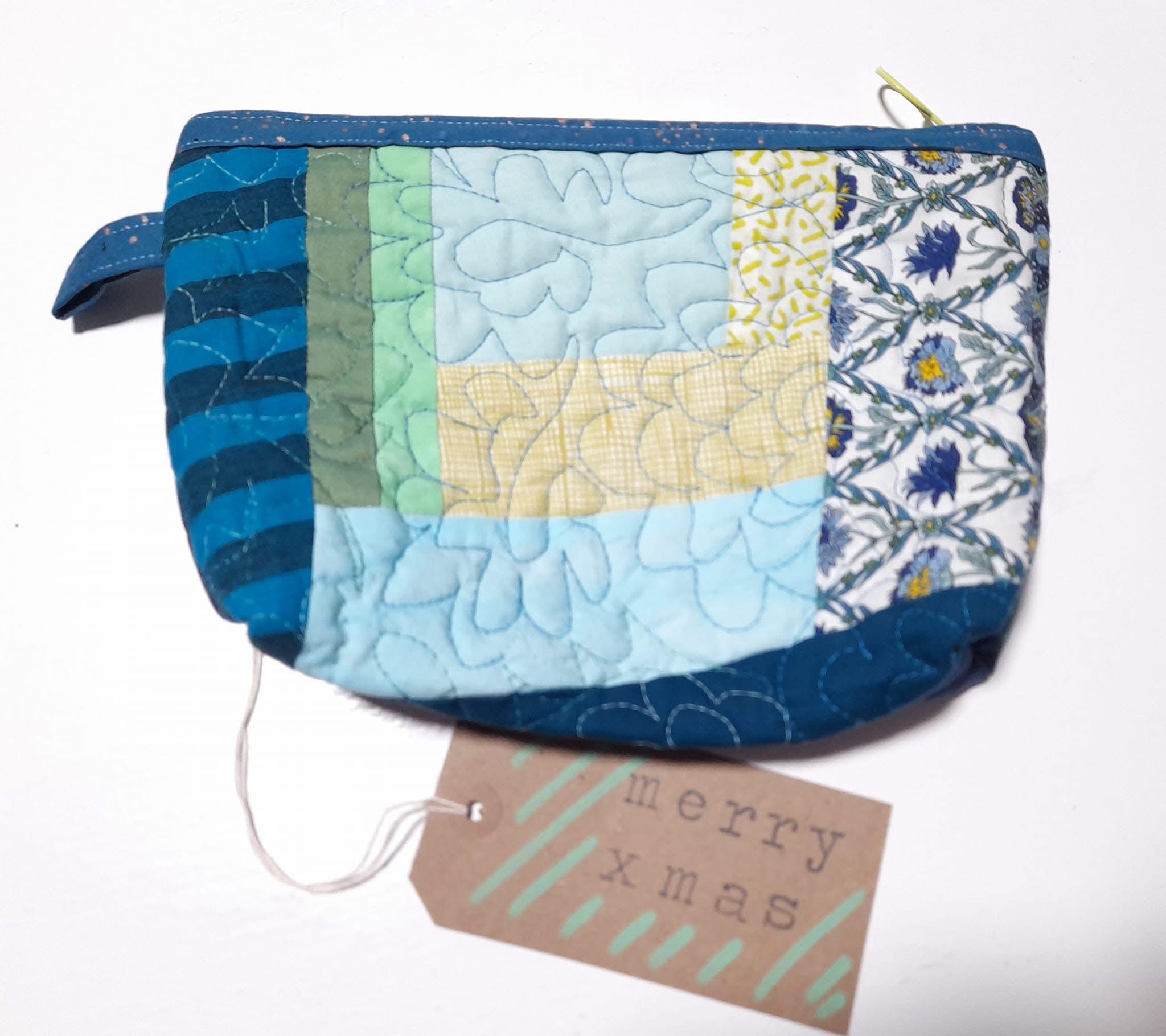 A patchwork zippered pouch made from different shades of blue and yellow.