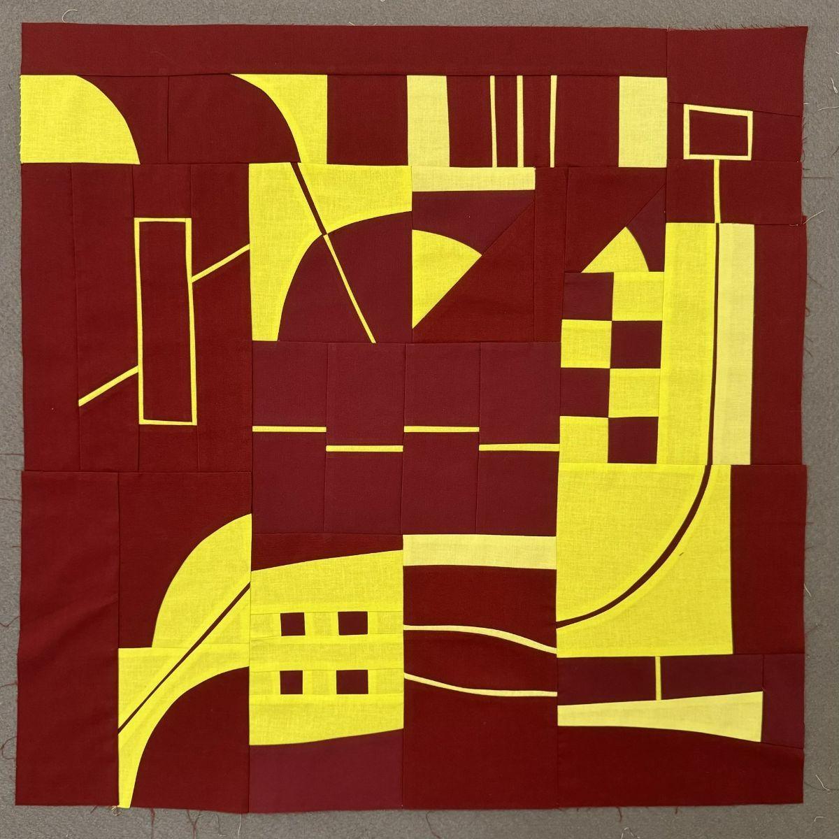 Pieced quilt top in deep red and bright yellow featuring abstract geometric shapes. The design includes lines, curves, triangles, rectangles, and squares arranged in a dynamic, improvisational style characteristic of Irene Roderick's "Dancing with the Wall" method