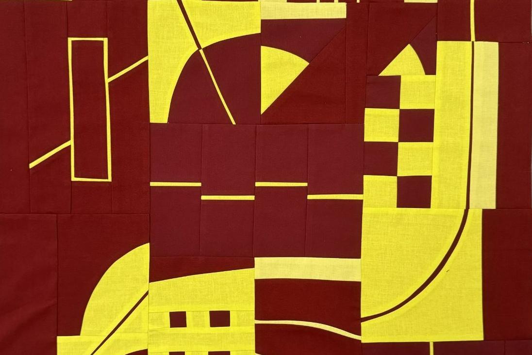 Pieced quilt top in deep red and bright yellow featuring abstract geometric shapes. The design includes lines, curves, triangles, rectangles, and squares arranged in a dynamic, improvisational style characteristic of Irene Roderick's "Dancing wi
