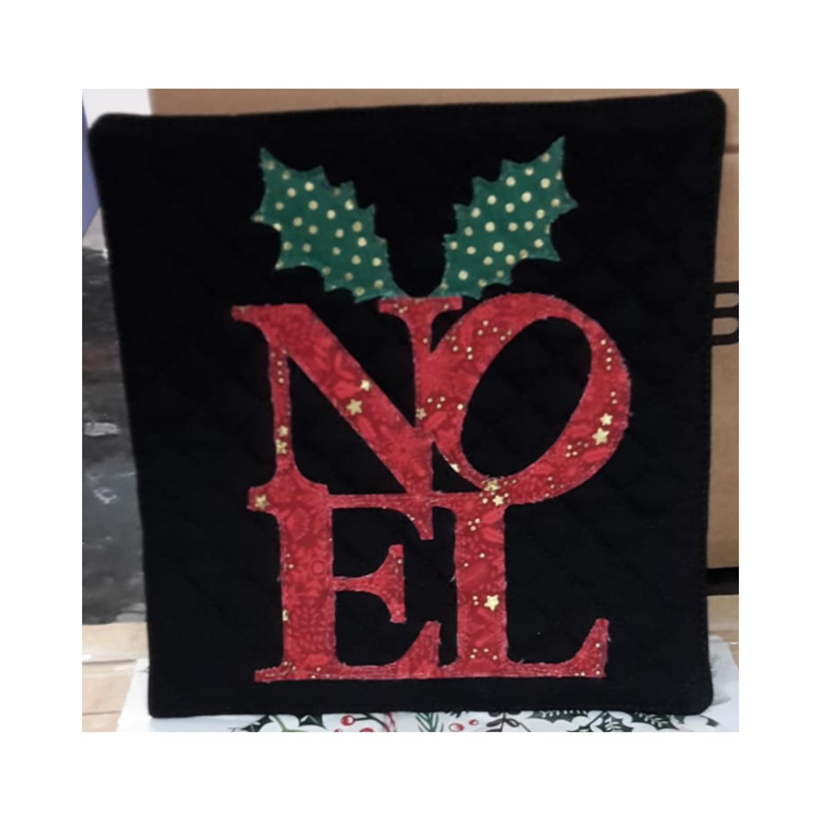 A square quilt with a black background. The word "NO&Euml;L" is spelled out in large, red letters, with a pair of green holly leaves at the top. The letters are decorated with gold stars and other embellishments.