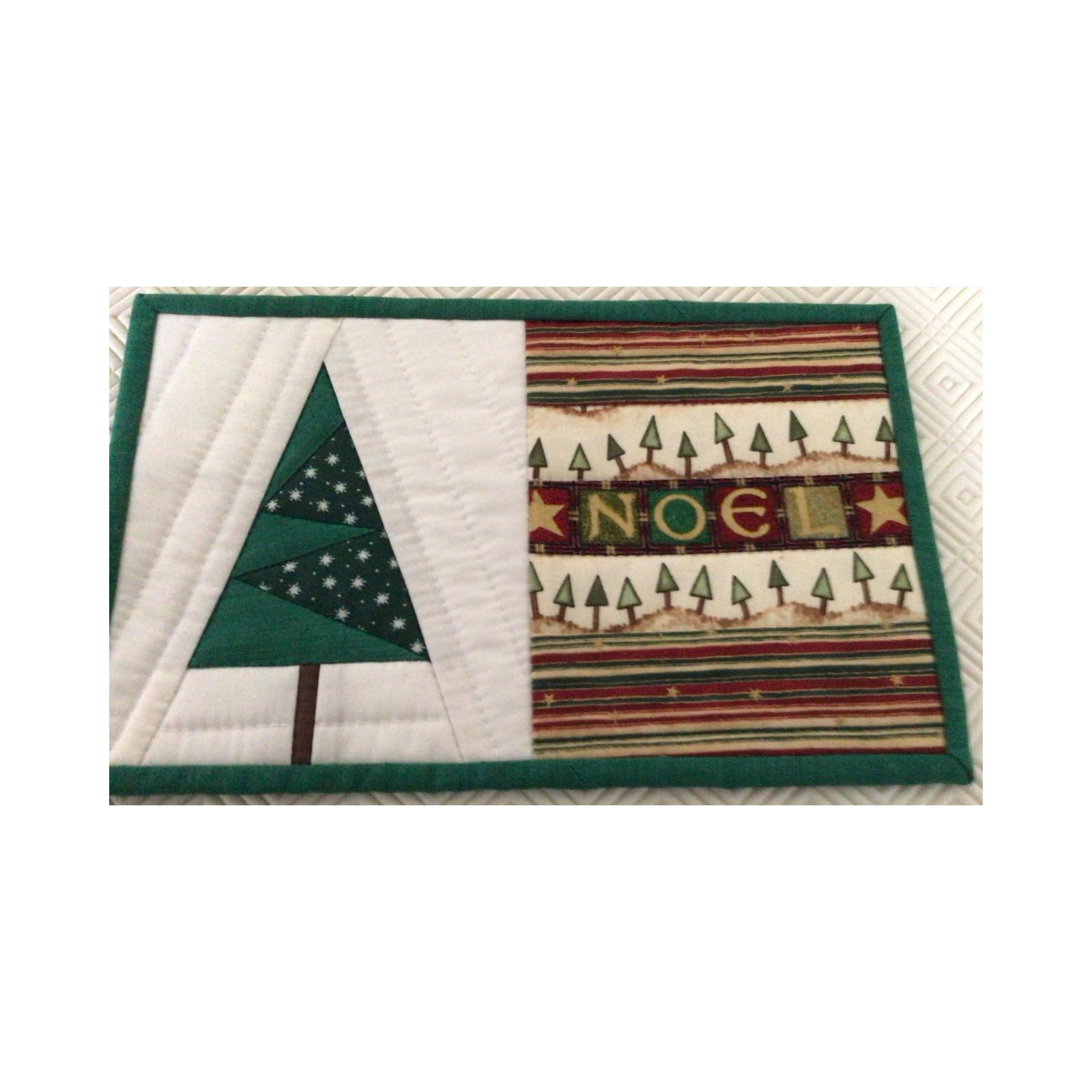 A rectangular quilt with a green border. The quilt is divided into two sections. The left section shows a green Christmas tree on a white background, while the right section features the word "NO&Euml;L" written in colorful letters on a striped background.