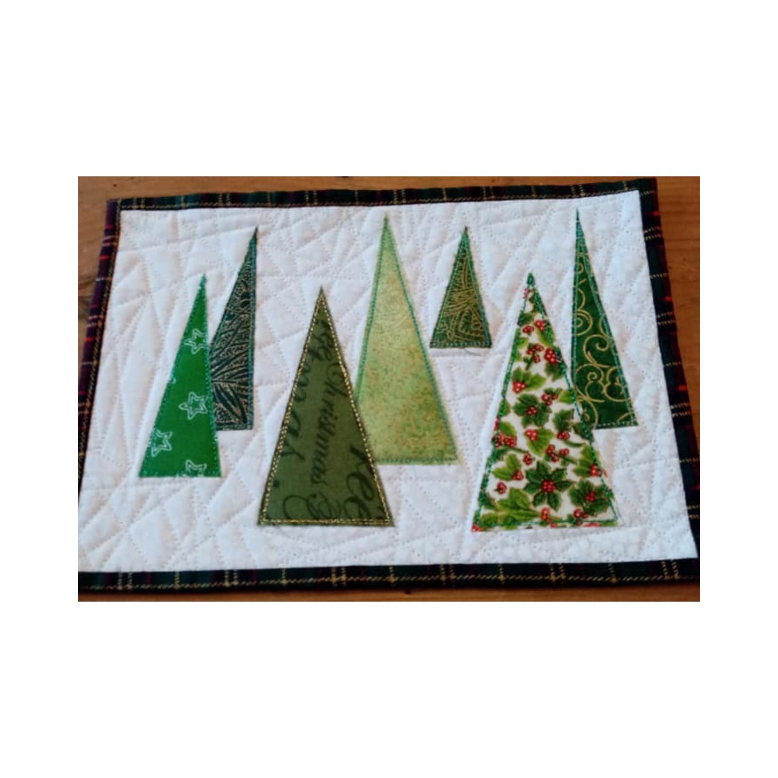 A rectangular quilt with a plaid border. The quilt features multiple Christmas trees of various sizes and patterns, all in shades of green. The background is a white fabric with a subtle, linear quilting pattern.