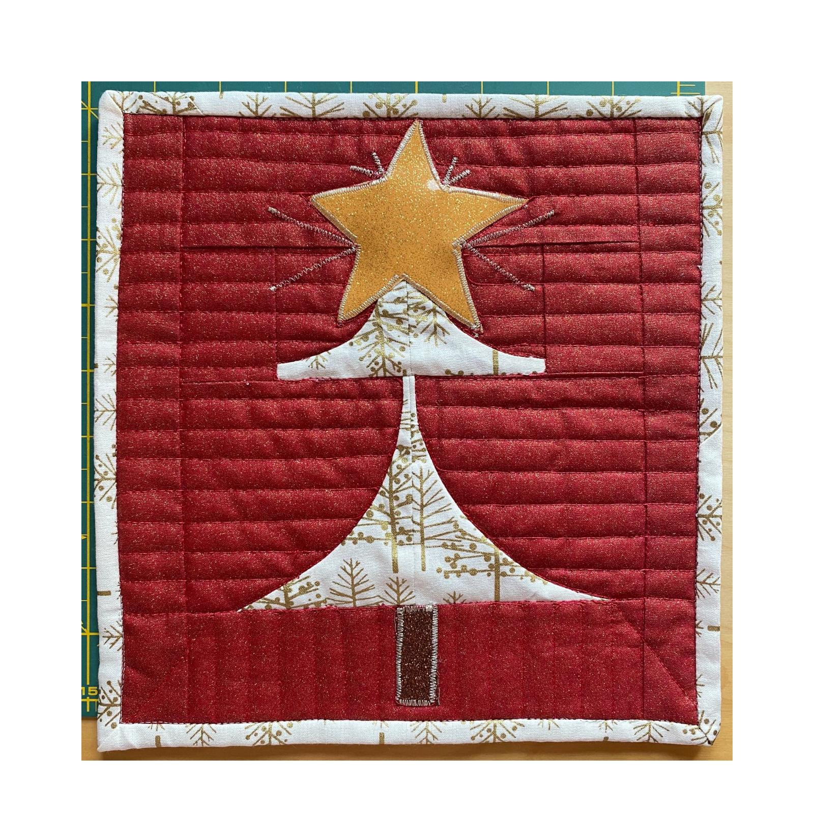 A square quilt with a red background and a gold border. The quilt features a gold star on top of a brown tree trunk. The tree trunk is surrounded by a white background with a gold pattern. The background is quilted with vertical lines.