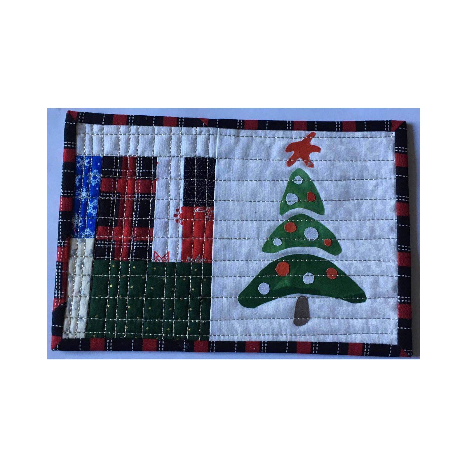 A rectangular quilt with a red and black plaid border. The quilt is divided into two sections. The left section features a patchwork design with squares in red, white, and blue, while the right section shows a green Christmas tree with white ornaments and a red star on top. The background is quilted with a grid pattern.