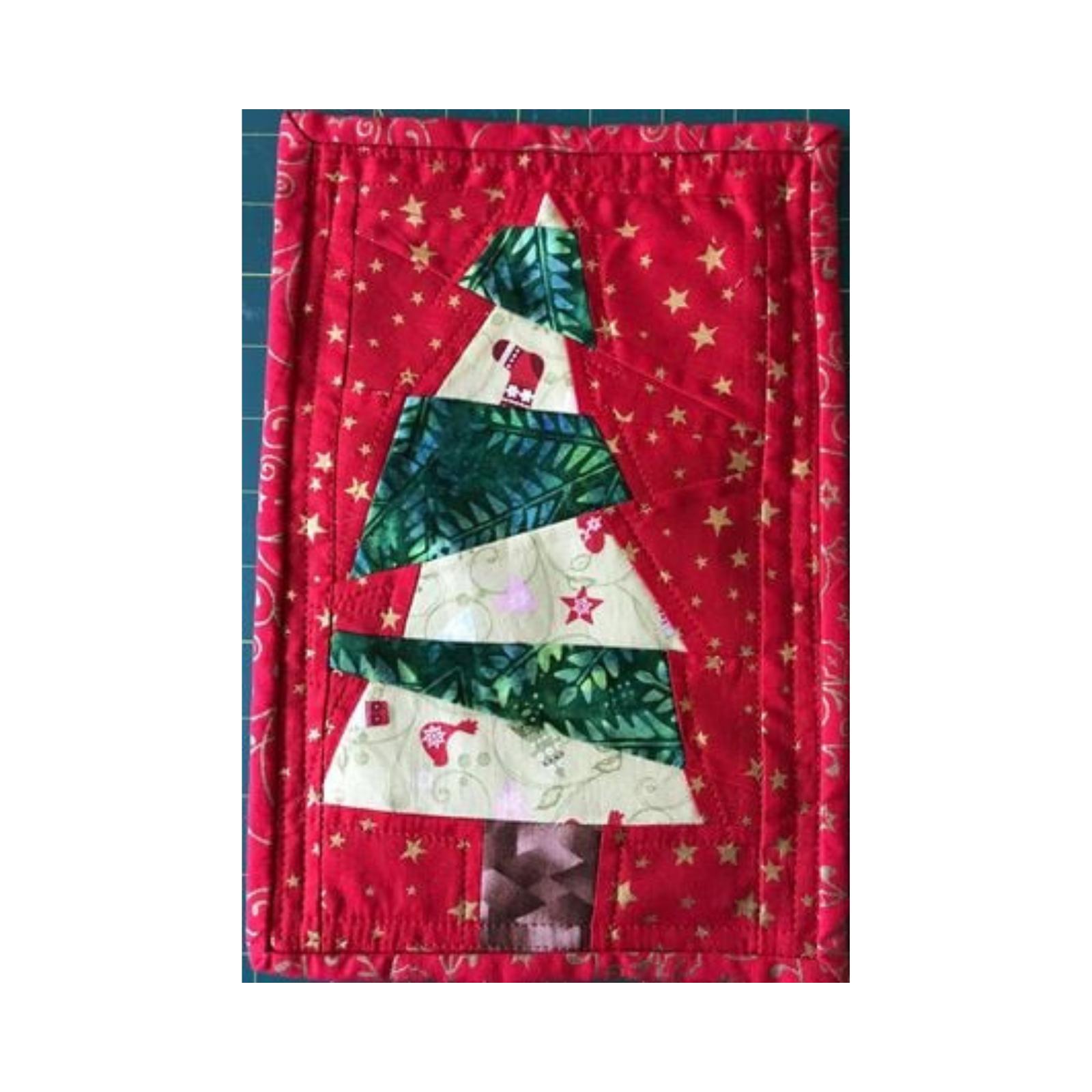 A rectangular quilt with a red background and a gold border. The quilt features a Christmas tree made up of green fabric triangles. The tree is decorated with small ornaments and has a brown trunk. The background is filled with small gold stars.