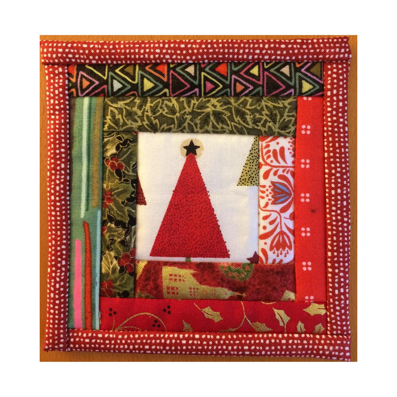 A square quilt with a red border. The quilt features a red Christmas tree in the center, surrounded by layers of fabric with various patterns, including stripes, polka dots, and flowers. The background is a white fabric with a subtle texture.