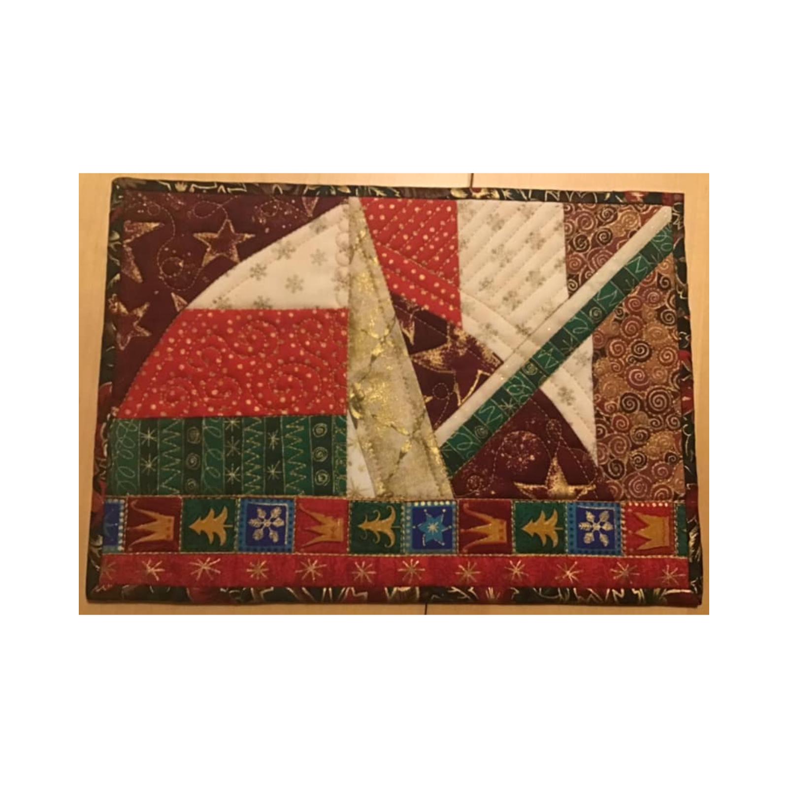 A rectangular quilt with a patchwork design. The quilt features various fabrics in red, green, gold, and white, with patterns like stars, stripes, and snowflakes. The pieces are arranged in a geometric pattern.