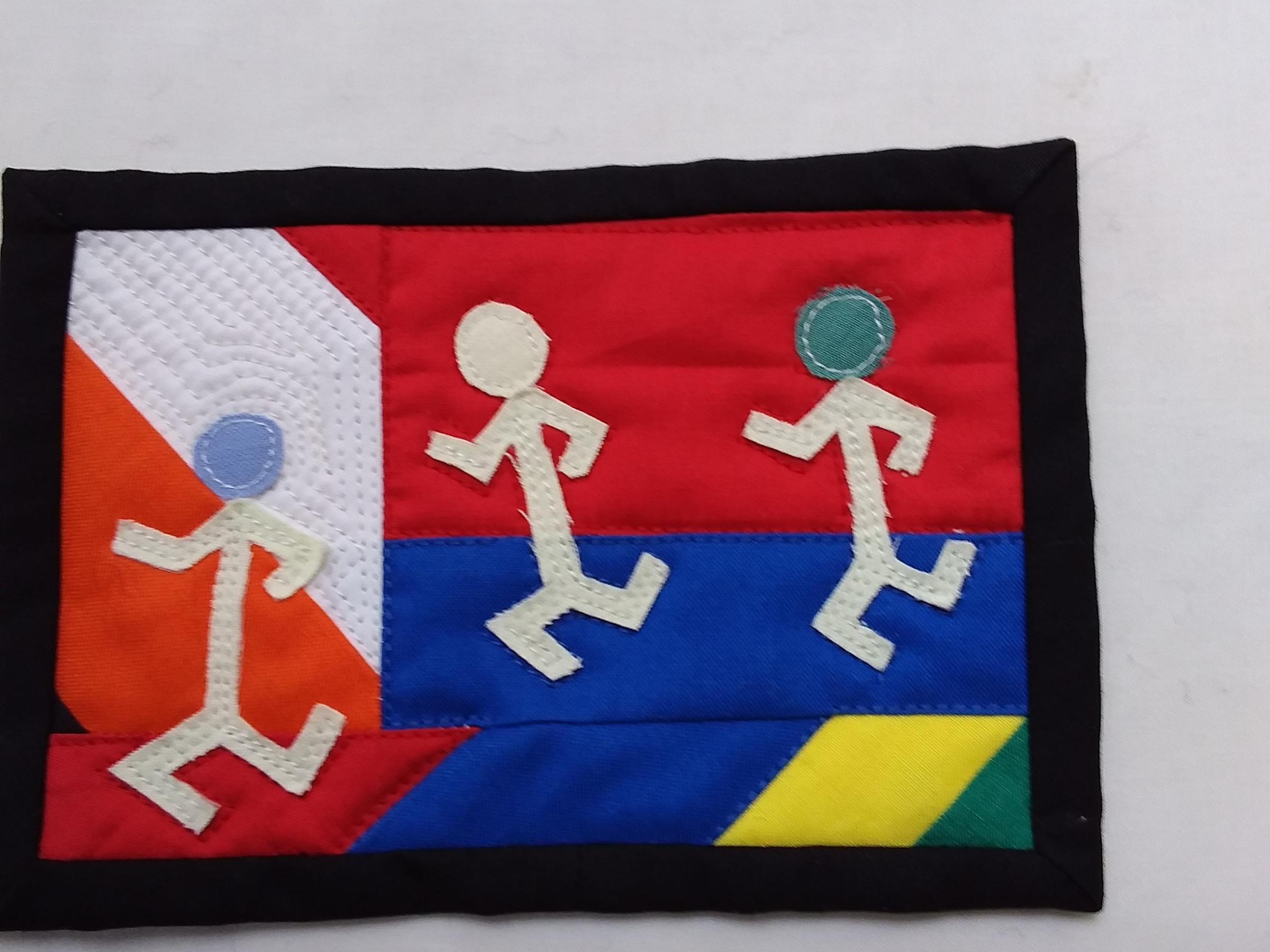 A postcard quilt with a multicoloured pieced background and a black border. The quilt features an, abstract design with three stick figures running.