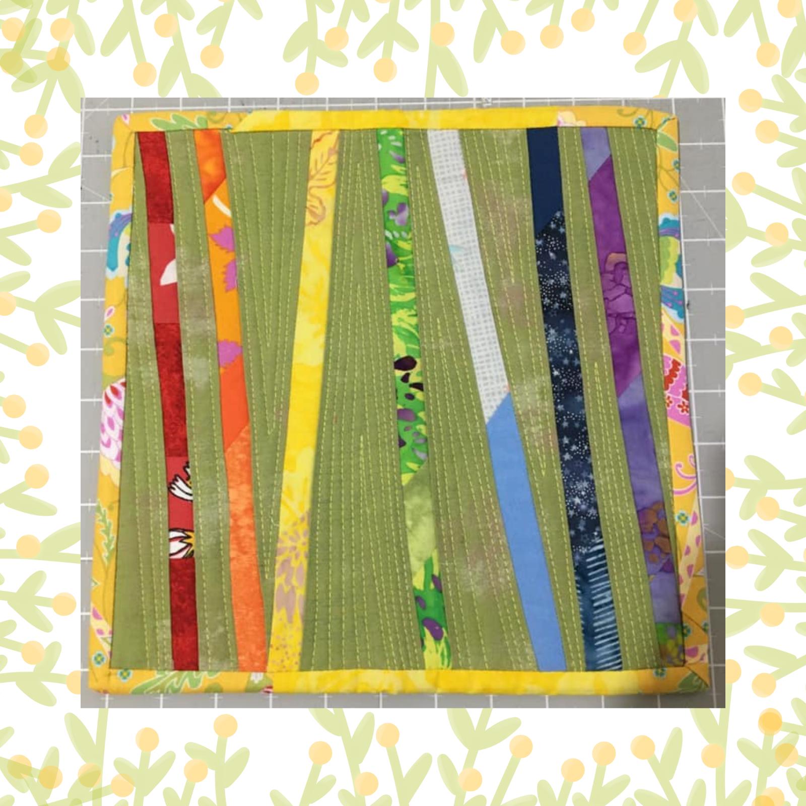 A rectangular quilt with a green background and a yellow border. The quilt features vertical strips of fabric in various colours, including red, orange, yellow, blue, and purple. The background is quilted with a linear pattern.