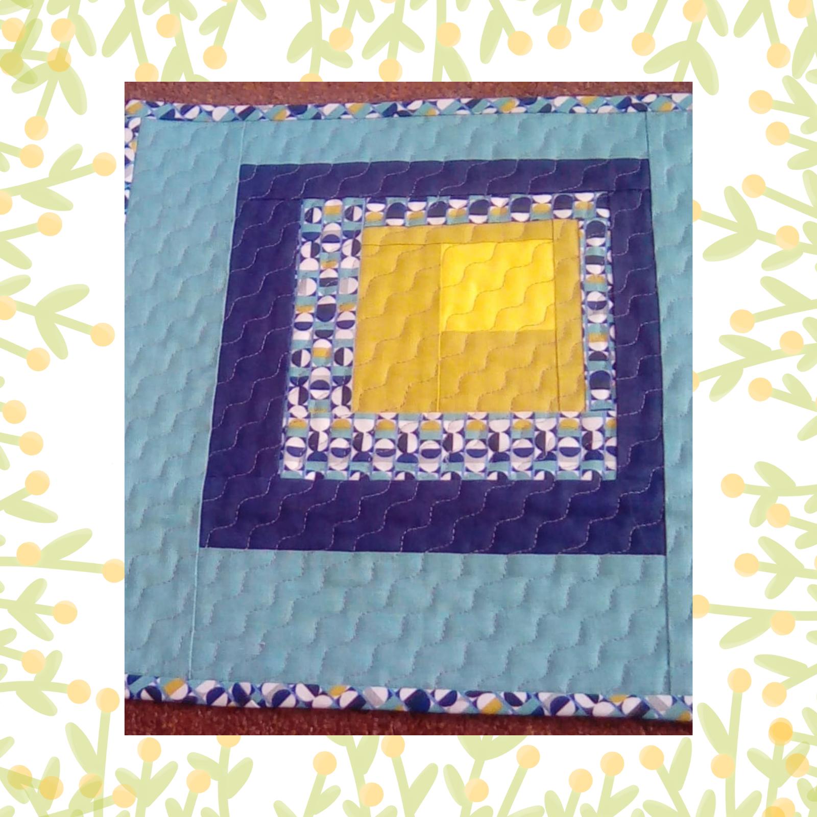 A square quilt with a blue background and a yellow border. The quilt features a nested square design, with each square getting smaller and featuring different patterns, including circles and stripes. The colours used are primarily blue and yellow. The background is quilted with wavy lines.