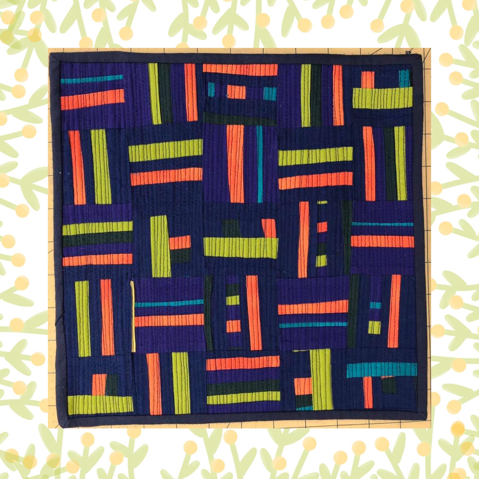 A square quilt with a dark blue background and a blue border. The quilt features a colourful geometric design with horizontal and vertical stripes in various colours, including orange, green, and blue. The background is quilted with a linear pattern.