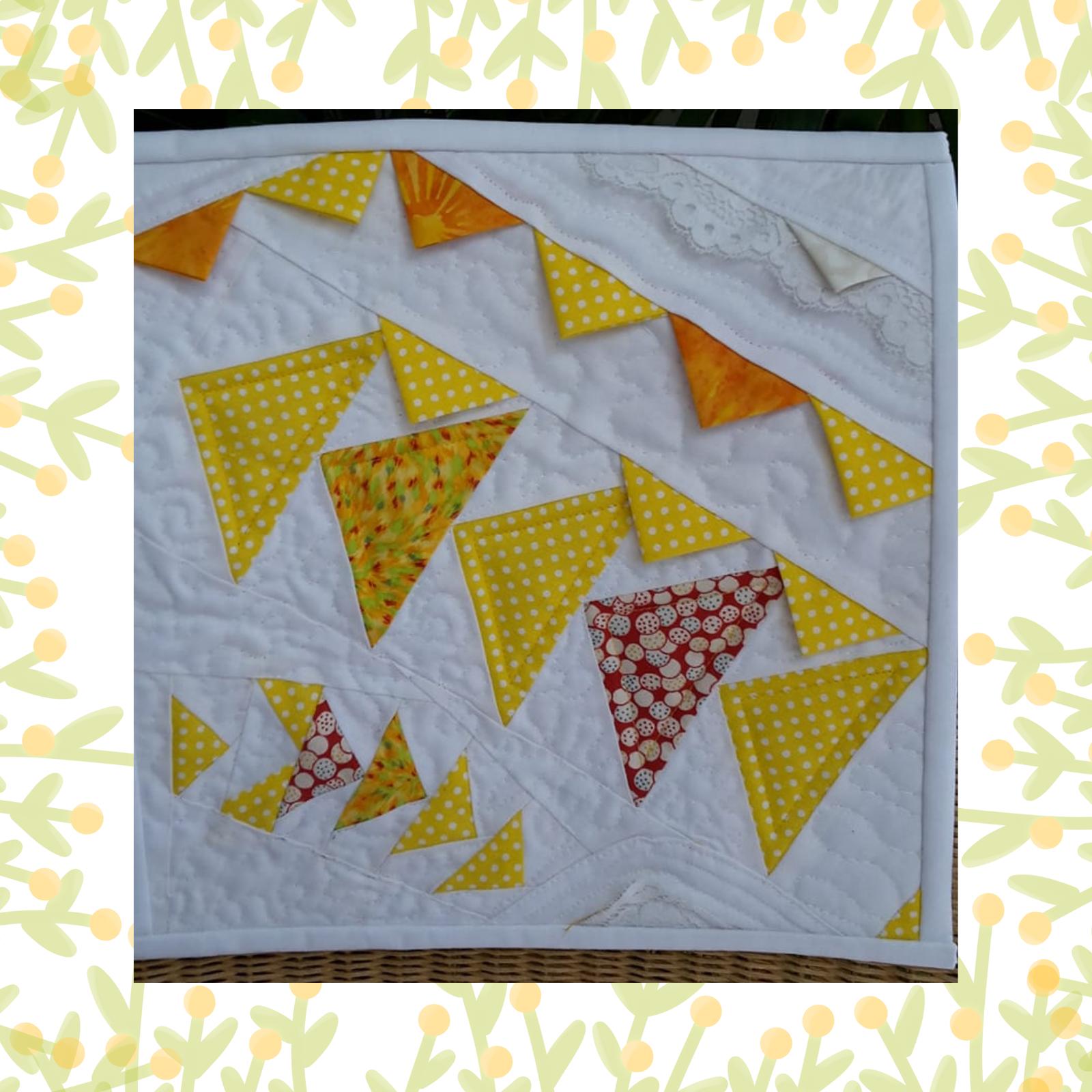 A square quilt with a white background. The quilt features a colourful, abstract design with triangles in shades of yellow, orange, and red. Some triangles have a polka dot pattern.