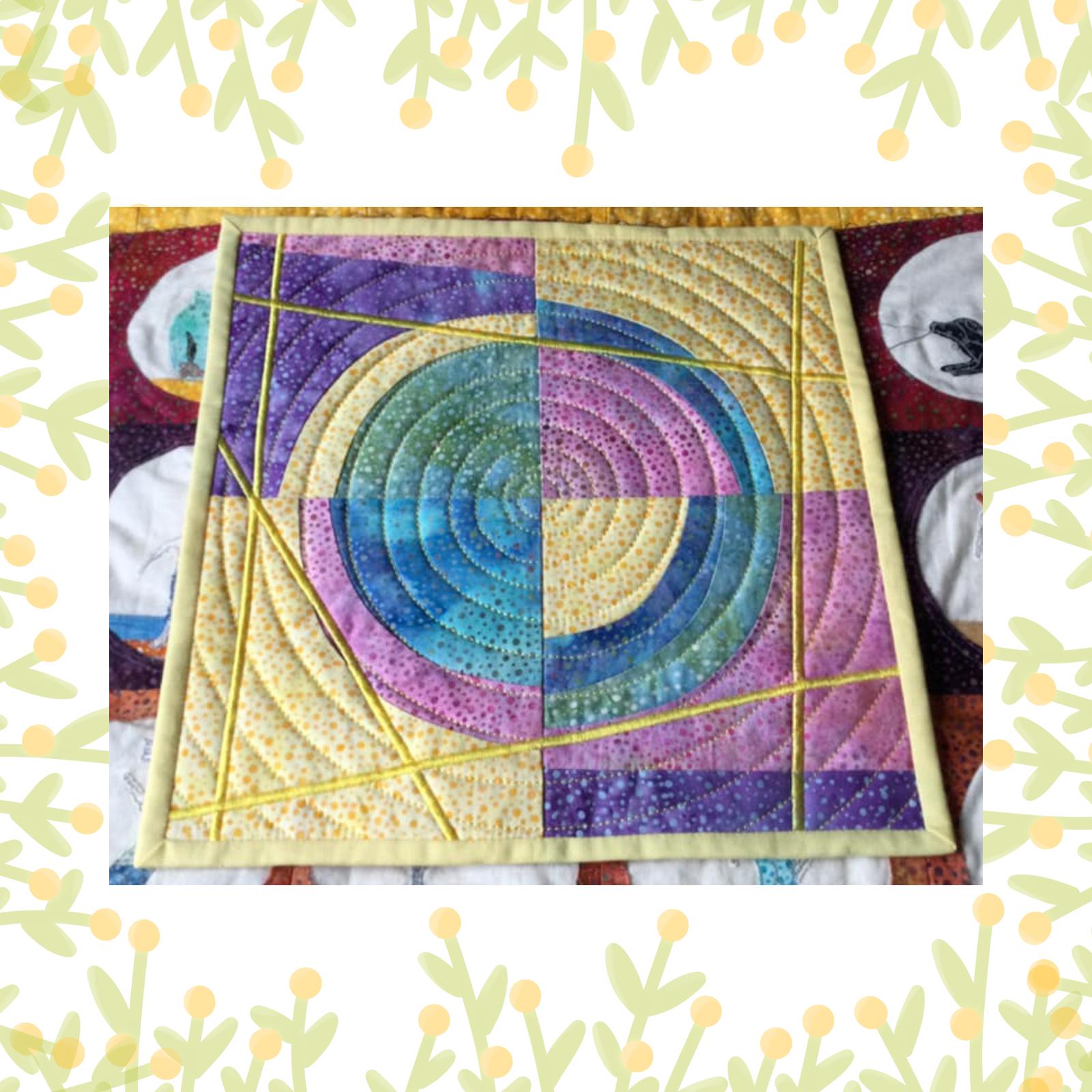 A square quilt with a yellow background and a purple border. The quilt features a circular design in the centre, made up of concentric circles in shades of blue and purple. The background is quilted echoing the shape of the quilt pieces.