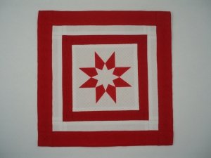 So, Here's to you, Mrs Sanderson by Dorian Walton: Quilt with a design of concentric squares in red and white with a star shape in the centre.