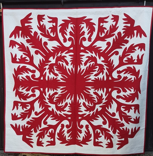 Quilt by Pippa Moss. Red damask style pattern on a white background