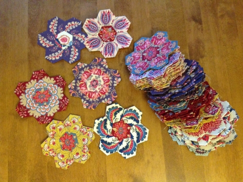 A selection of hexagonal quilt pieces on a table in various coloured and patterned fabric