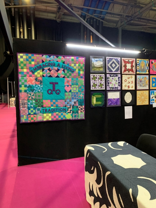 A selection of quilts, including the Traditional Quilt Group banner quilt, displayed on an exhibition wall