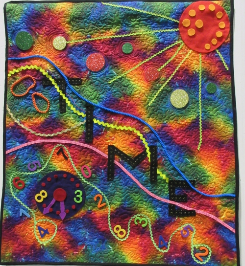 Square quilt with rainbow coloured tie-die background with the work 'Time' and a clock and numbers in the foreground