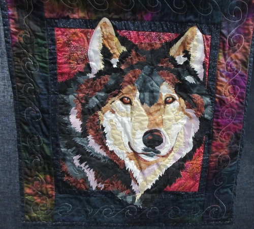 Quilt depicting a dogs face on a dark red and black background