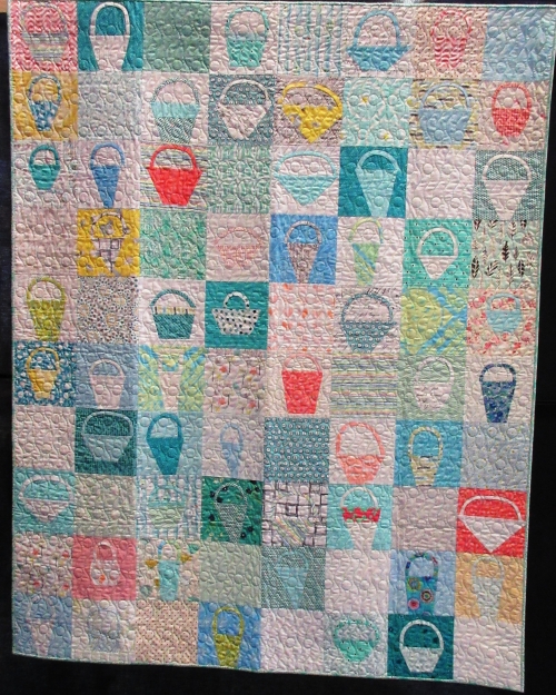 Quilt made of pastel coloured squares each displaying a basket shape