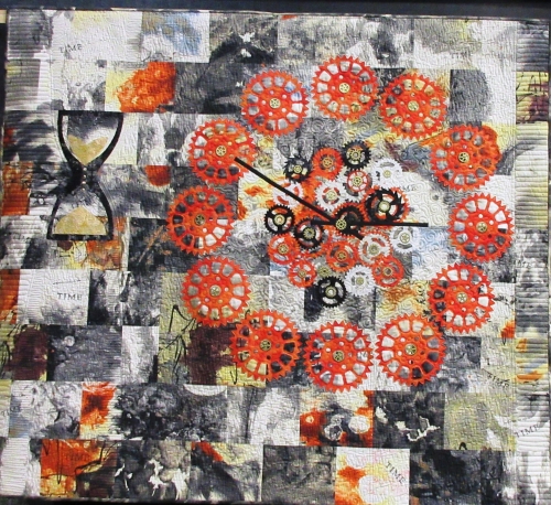 Quilt made of grey, white and yellow squares with the image of a clock depicted using orange cogs