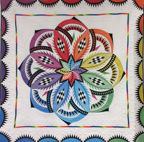 Quilt with white background and rainbow flower in the centre