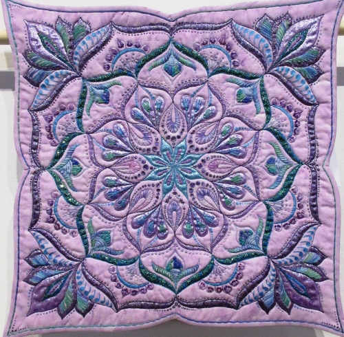 Lilac square quilt with a floral pattern in purple, blue and green