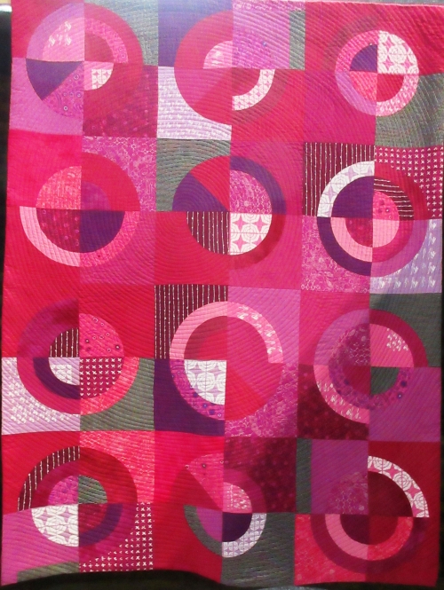 Quilt with design of squares and circles in different shades of pink
