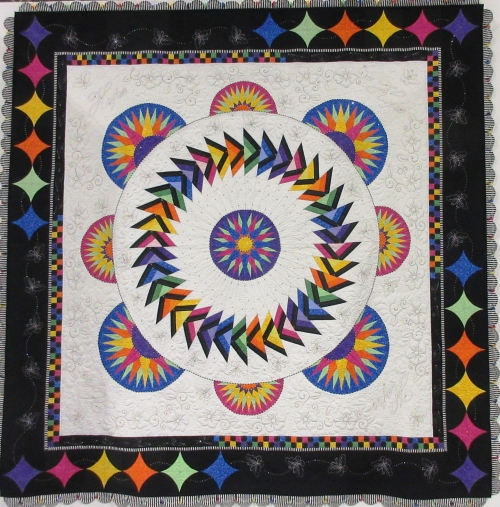 Square quilt with wide black border, white background and rainbow sun motifs