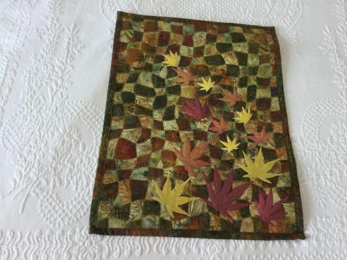 Dark green and yellow quilt with red and yellow autumn leaves